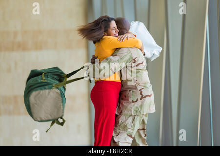Afrikanische amerikanische Soldat umarmt Frau im Flughafen Stockfoto