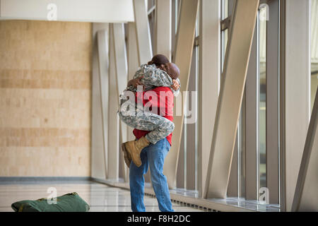Afrikanische amerikanische Soldat umarmt Mann im Flughafen Stockfoto