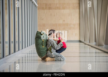Afrikanische amerikanische Soldat umarmt Sohn im Flughafen Stockfoto
