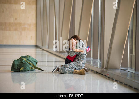 Afrikanische amerikanische Soldat umarmt Sohn im Flughafen Stockfoto