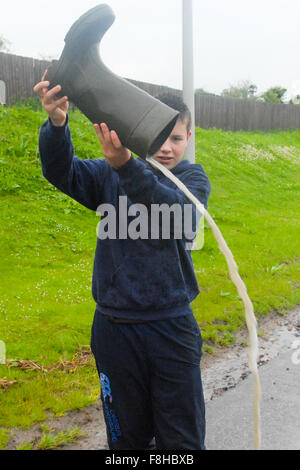Junge gießt Wasser aus der Gummistiefel in Alford in Aberdeenshire, Schottland. Stockfoto