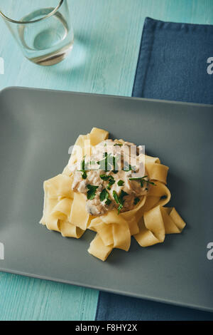 Pasta mit Pilzen und Sahne auf grauen quadratischen Teller Stockfoto