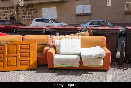Sofa und Tür links in der Nähe communial Müllcontainer in der Straße in Spanien Stockfoto