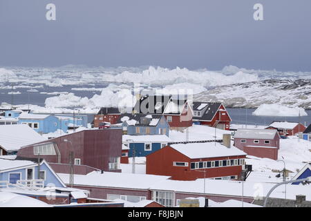 Ilulissat farbenfrohe Stadthäuser hinter Eisbergen, die in der Disko Bay, Grönland, schweben Stockfoto