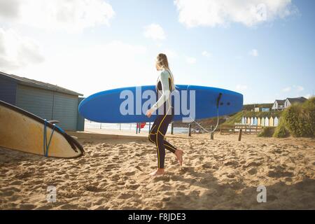 Weibliche Surfer am Strand, mit Surfbrett Stockfoto
