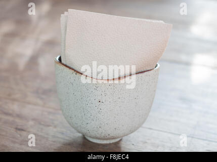 Seidenpapier in Keramik Tasse auf Holztisch, Fotoarchiv Stockfoto