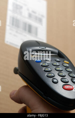 Barcode-Scanner-Leser mit jemandes Hand scannen einen UPC bar Code Label auf einem Feld Stockfoto