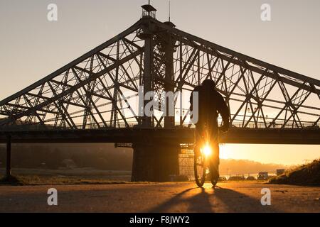 Dresden, Deutschland. 10. Dezember 2015. Ein Radsportler vor der "Blaues Wunder" Brücke über die Elbe bei Sonnenaufgang, in Dresden, Deutschland, 10. Dezember 2015. Foto: SEBASTIAN KAHNERT/DPA/Alamy Live-Nachrichten Stockfoto