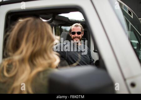 Über die Schulter-Blick der jungen Frau im Gespräch mit Freund im jeep Stockfoto