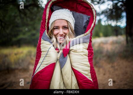 Porträt der jungen Frau mit Stricken Hut gewickelt im Schlafsack, Lake Tahoe, Nevada, USA Stockfoto