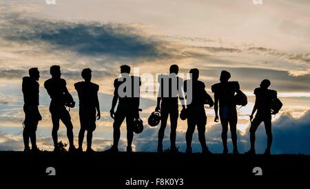 Silhouette der Gruppe der jungen amerikanischen Fußballspieler, stehend in Reihe Stockfoto