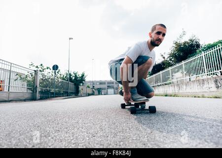 Junger Mann hockte auf skateboard Stockfoto