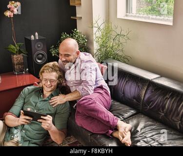 Romantischen männlichen Partner liegend auf Sofa Blick auf digital-Tablette Stockfoto