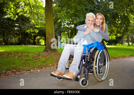 Enkelin umarmen ihre Großmutter im Rollstuhl im freien Stockfoto