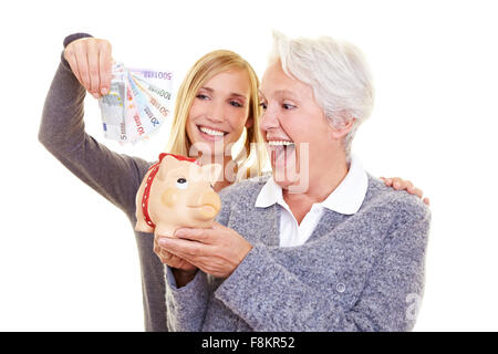 Junge und alte Frau, Geld im Sparschwein für Rente Stockfoto