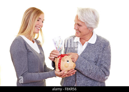 Großmutter, Geld im Sparschwein ihrer Enkelin Stockfoto