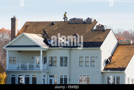 Arbeiter auf einem amerikanischen Hausdach entfernen der alten Schindeln und fühlte sich bereit, das Dach, USA zu ersetzen Stockfoto