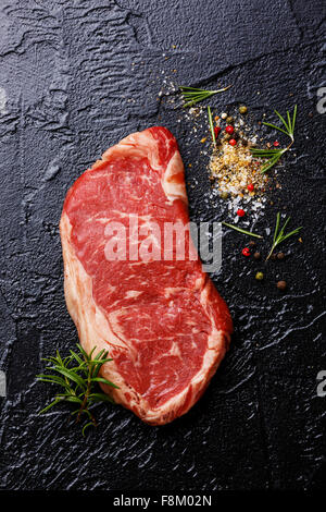 Rohes Frischfleisch Striploin Steak mit Gewürzen auf schwarzem Hintergrund Stockfoto