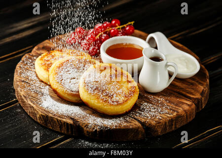 Hausgemachter Hüttenkäse Pfannkuchen russische Syrniki mit süßen Saucen auf hölzernen Hintergrund Stockfoto