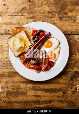 Englisches Frühstück mit Spiegelei, Würstchen, Speck, Bohnen, Toast, Tomaten und Pilze auf Holz Hintergrund Stockfoto