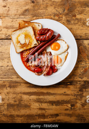 Englisches Frühstück mit Spiegelei, Würstchen, Speck, Bohnen, Toast, Tomaten und Pilze auf Holz Hintergrund Stockfoto