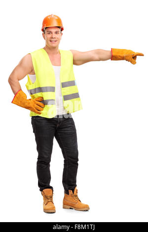 In voller Länge Portrait von jungen männlichen Bauarbeiter mit seiner Hand nach rechts zeigenden und schaut in die Kamera Stockfoto