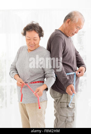 asiatische älteres paar Bauch mit Maßband messen Stockfoto