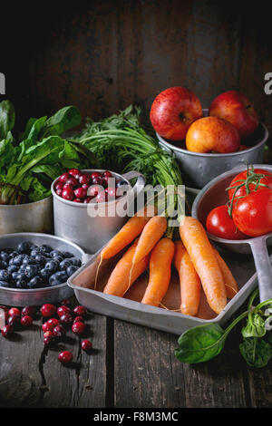 Auswahl an frischem Obst, Gemüse und Beeren. Reihe von Karotten, Spinat, Tomaten und rote Äpfel, Heidelbeeren und Heidelbee Stockfoto