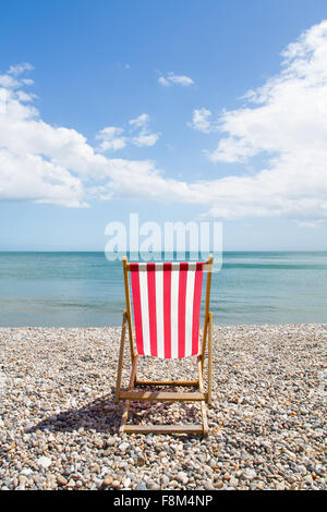 Einzigen rot-weiß gestreiften Liegestuhl auf einem einsamen Kieselstrand. Stockfoto