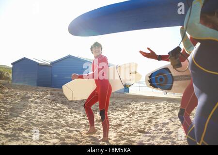 Gruppe von Surfern am Strand tragen Surfbretter Stockfoto