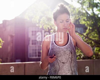 Junge Frau mit Kopfhörern hören Stockfoto