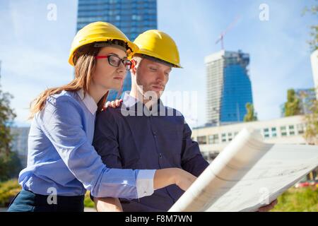 Bauunternehmen tragen Schutzhelme Blaupause betrachten Stockfoto