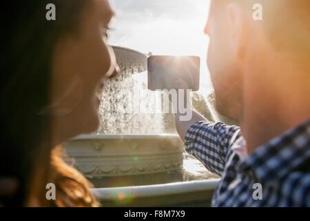 Paar nehmen Selfie auf Handy, Brunnen im Hintergrund Stockfoto