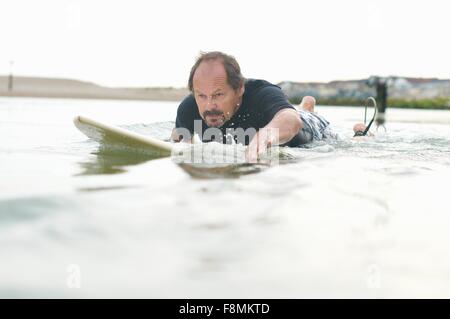 Surfer paddeln Surfbrett heraus zum Meer Stockfoto