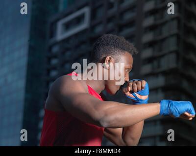 Porträt von Boxer werfen Schlag, Gebäude im Hintergrund Stockfoto