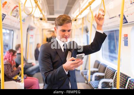 Geschäftsmann SMS auf Rohr, London Underground, UK Stockfoto