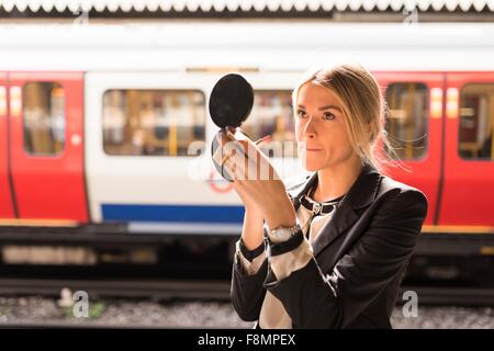 Geschäftsfrau Pudern Nase, London Underground, UK Stockfoto