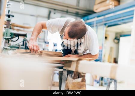 Junger Mann in der Werkstatt nach unten zählen Sperrholzplatten Stockfoto