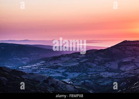 Orange Sonnenuntergang über Meer und zerklüftete Gebirge Ackerland, Castelsardo, Sardinien, Italien Stockfoto