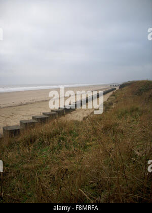 Weltkrieg zwei Panzerfallen aus Beton an der Ostküste Englands. In einer geraden Linie am Rande des Strandes. Blauer Himmel mit weißen Wolken als Hintergrund. Stockfoto