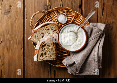 Clabber Sauermilch und braune Roggenbrot auf Korbwaren Tablett auf hölzernen Hintergrund Stockfoto