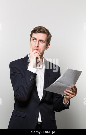 Blonden europäischen Geschäftsmann mit einer Suche suchen Blicke in die Ferne mit einem Stück Papier in der Hand während vor Stockfoto