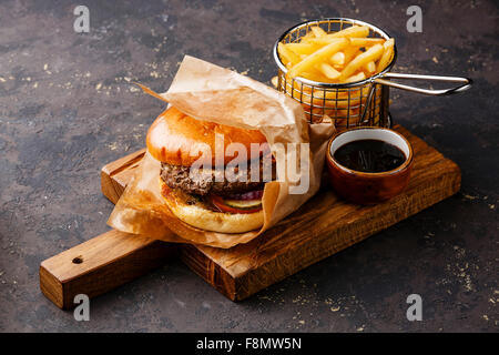 Burger mit Fleisch und Pommes frites im Korb auf dunklem Hintergrund dienen Stockfoto