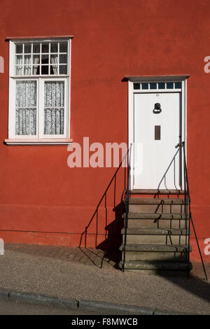 Detail des rot-Orange lackiert Hütte mit Steinstufen, Tür in Lavenham Suffolk England Stockfoto