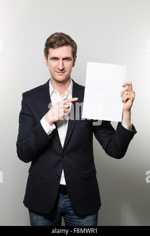 Blonden europäischen Geschäftsmann zeigt etwas auf ein Stück Papier und nimmt einen überzeugenden Blick in die Kamera, während in her Stockfoto