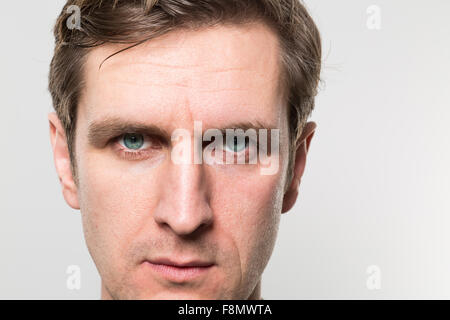 Nahaufnahme eines blonden europäischen Geschäftsmann mit ernstem Gesicht in die Kamera vor einem Farbverlauf Hintergrund Stockfoto
