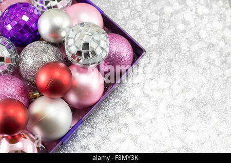 Bunte Weihnachtskugeln in einer Schüssel vor glänzenden silbernen Hintergrund Stockfoto