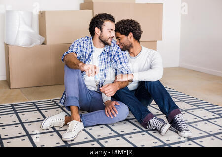 Glückliche Schwule paar auf Boden sitzend Stockfoto