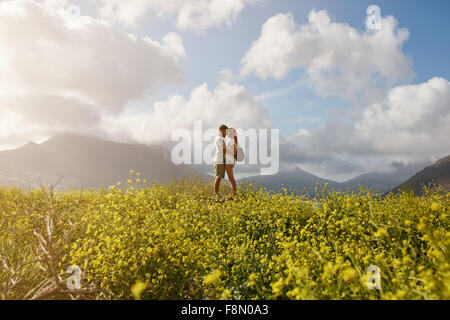Romantische junges Paar umarmt und sahen einander, stehend auf einem Hügel im Freien an einem Sommertag. Junger Mann und Stockfoto