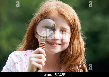 Mädchen auf der Suche durch Lupe mit vergrößerten Augen Stockfoto